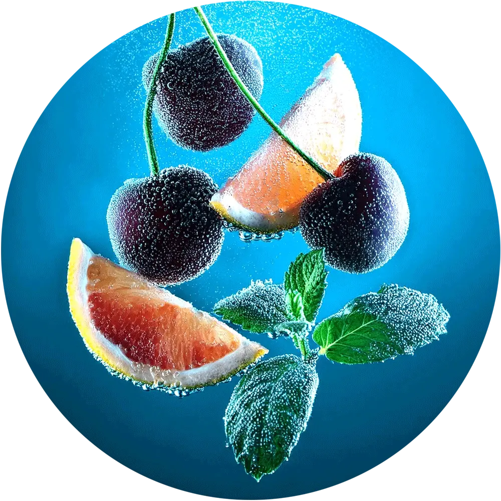 Drei dunkle Kirschen und zwei Orangenscheiben sind unter Wasser mit Bläschen zu sehen.