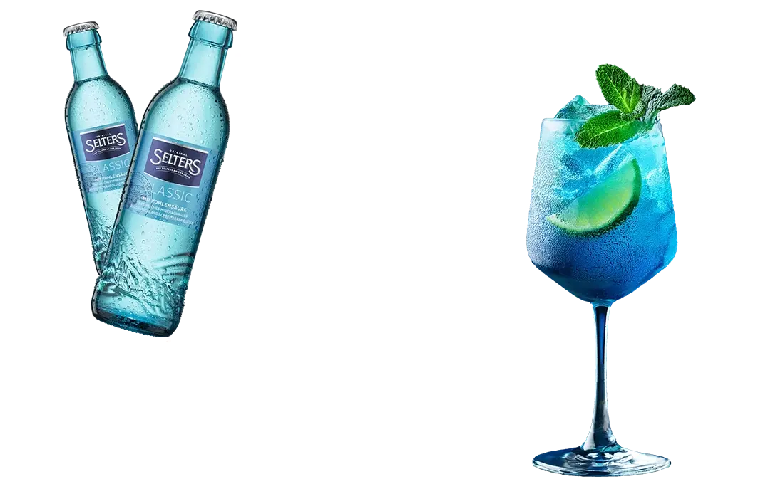 Zwei blaue Flaschen stehen links und ein gefülltes Glas rechts mit Limettenscheibe und Minze.