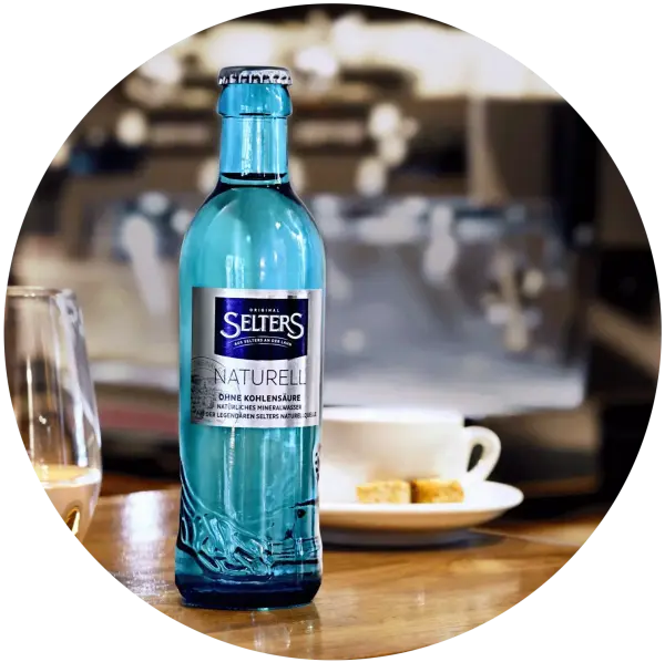 Eine blaue Mineralwasserflasche steht auf einem Tisch in einem Café.