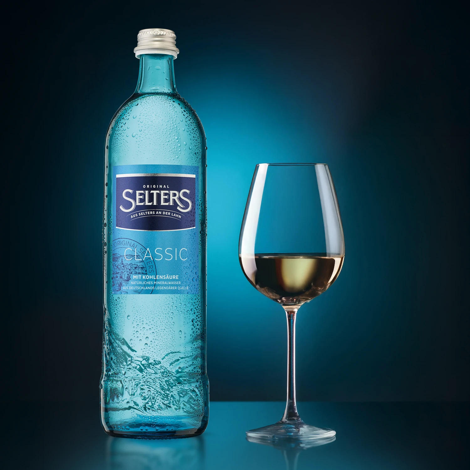 Eine wasserbedeckte Glasflasche steht neben einem gefüllten Weinglas.