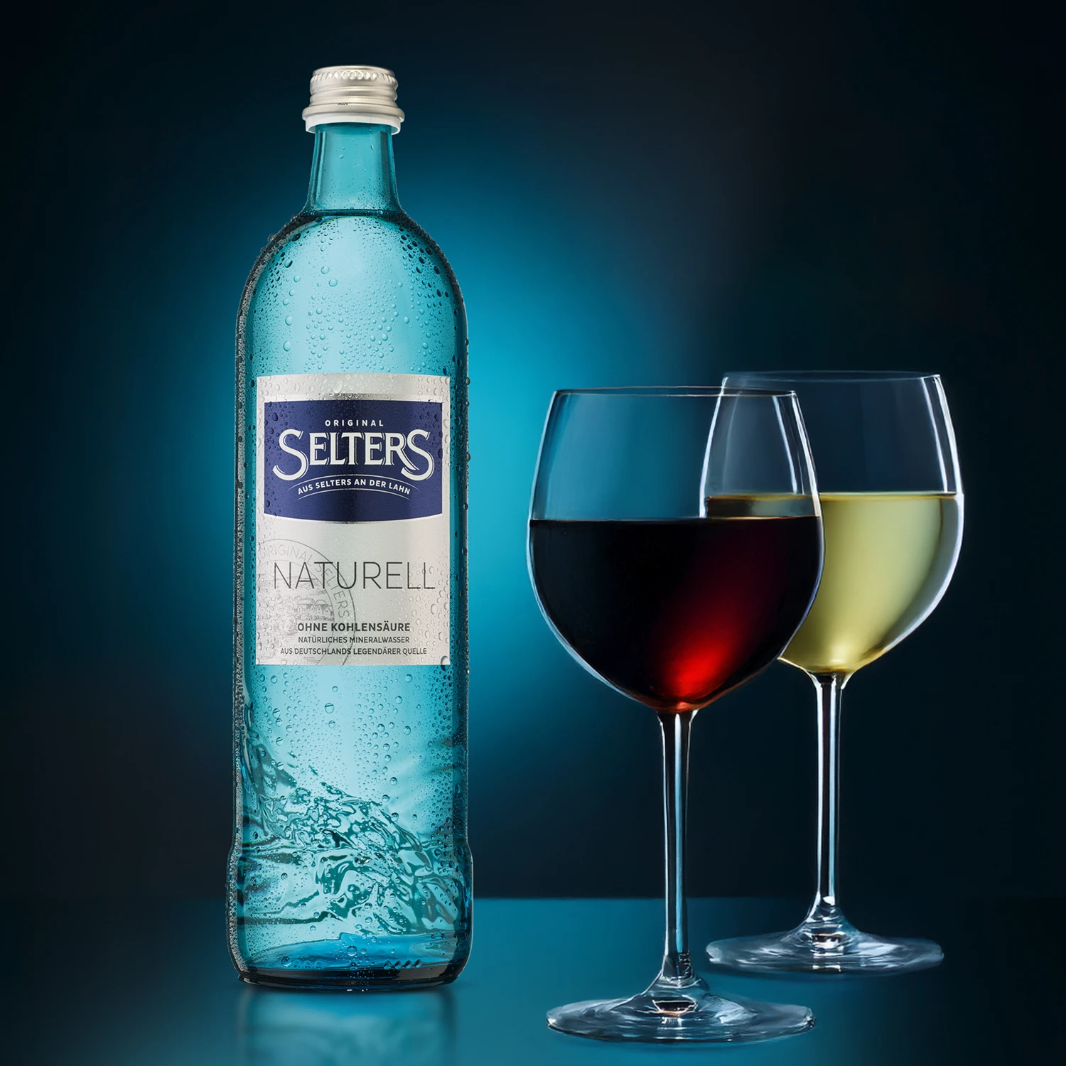 Eine gefüllte Wasserflasche steht neben zwei Weingläsern mit rotem und weißem Wein.