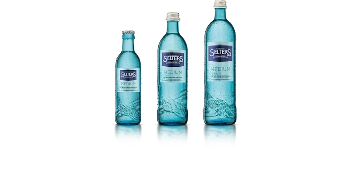 Vier Flaschen mit Mineralwasser in verschiedenen Größen stehen nebeneinander. Die Flaschen sind durchsichtig und mit blauer Flüssigkeit gefüllt.