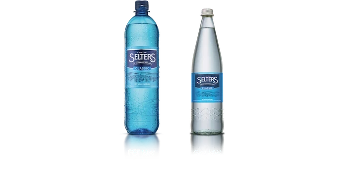 Zwei gefüllte Wasserflaschen stehen nebeneinander, eine aus blauem Kunststoff, die andere aus Glas.