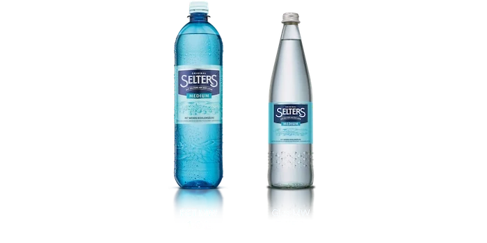 Zwei Mineralwasserflaschen stehen nebeneinander, eine aus Kunststoff, die andere aus Glas.